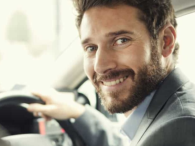 Ein Mann lächelt am Lenkrad eines Autos.